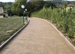 Strada drenante a Firenze, fiancheggiata da prato e lampioni a sinistra, e siepi a destra, in un contesto residenziale contemporaneo.