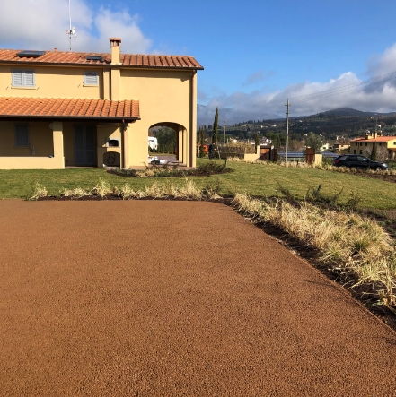 Pavimento drenante all'esterno di un'abitazione, con giardino e vista su colline, in un contesto residenziale.