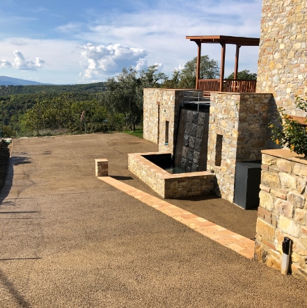 Resede drenante di una villa con muri in pietra, circondata da una rigogliosa flora collinare.
