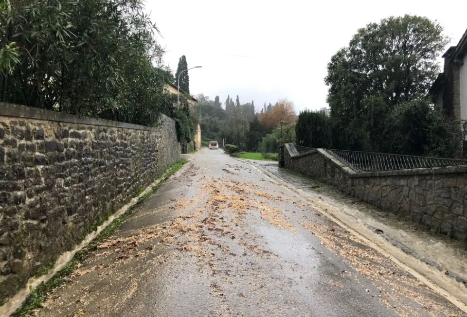 104 Rischi legati al trascinamento di detriti su strada bagnata, circondata da muri in pietra e vegetazione